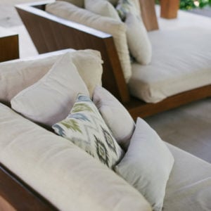 Cushions of various textures and plain colours on modern wooden frame garden furniture